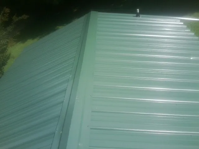 New green metal panels meeting at the ridge of a roof — Flat Roof Repair work by our crew in Lewellen