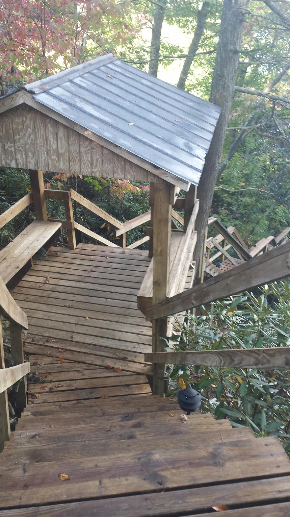 Metal roofed shelter over wooden steps on a wooded walkway — Skylight Repair & Installation work by our crew in Lewellen