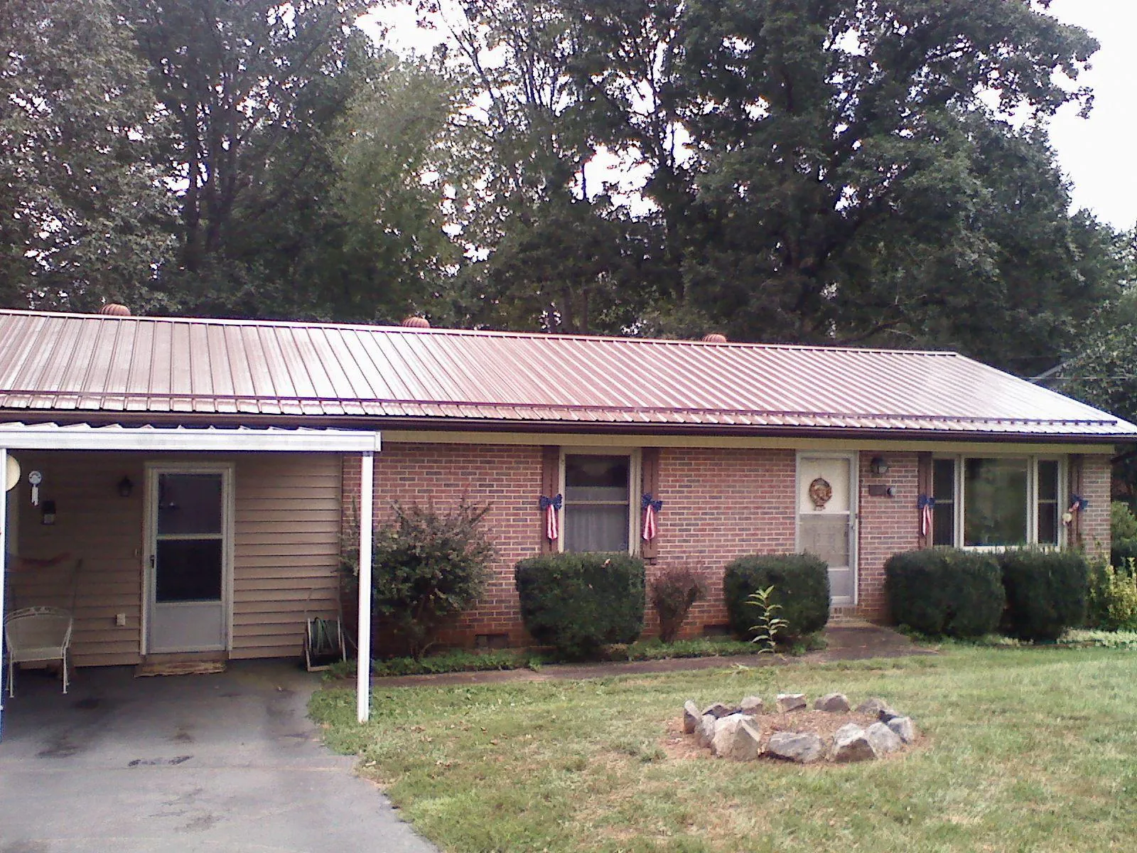 Bronze metal roof and carport on a brick ranch home — Roof Repair work by our crew in Lewellen