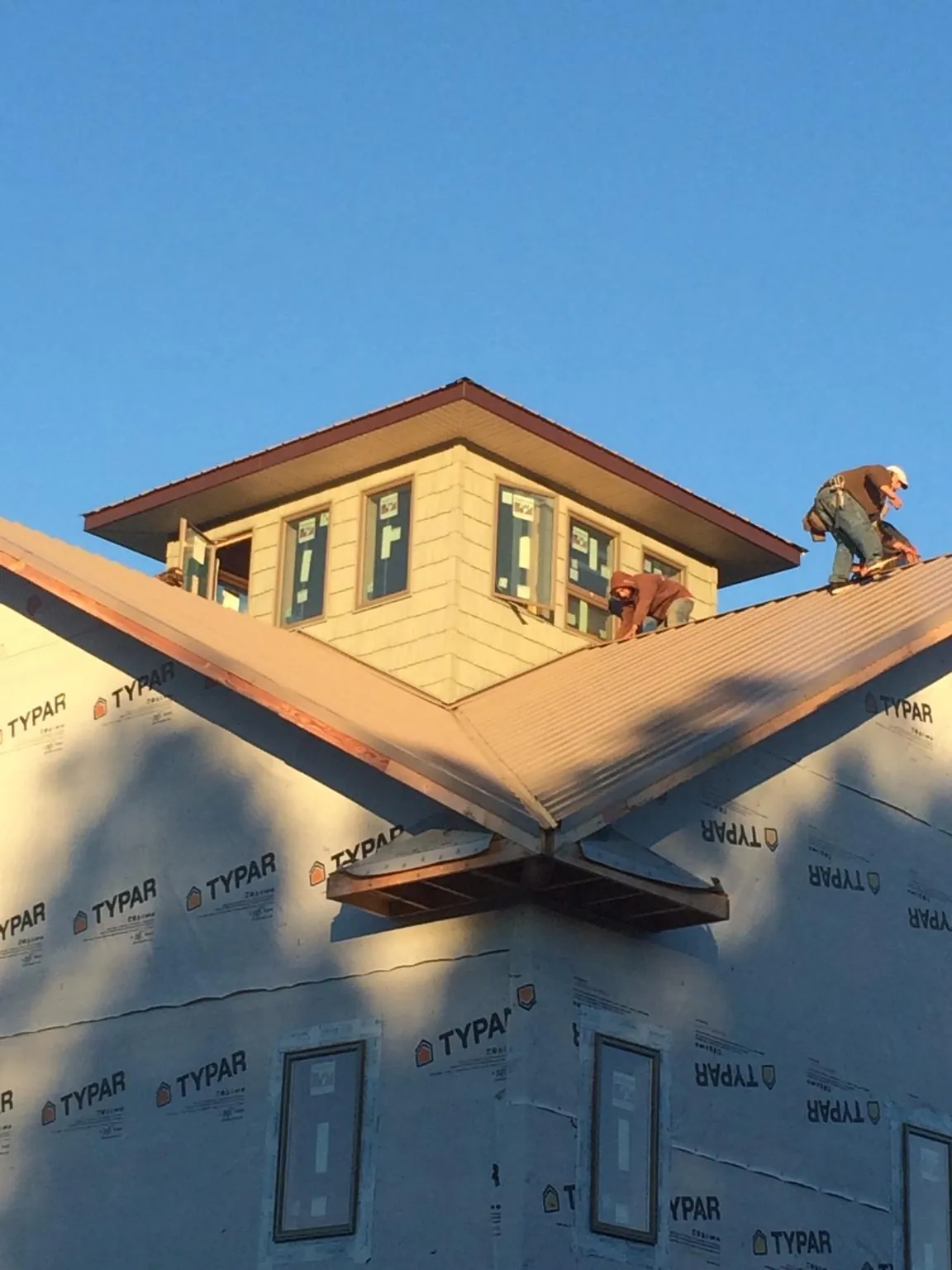 Roofers working around a rooftop cupola on a new metal roof at sunset — Roof Waterproofing in Lewellen by Roofing Brothers